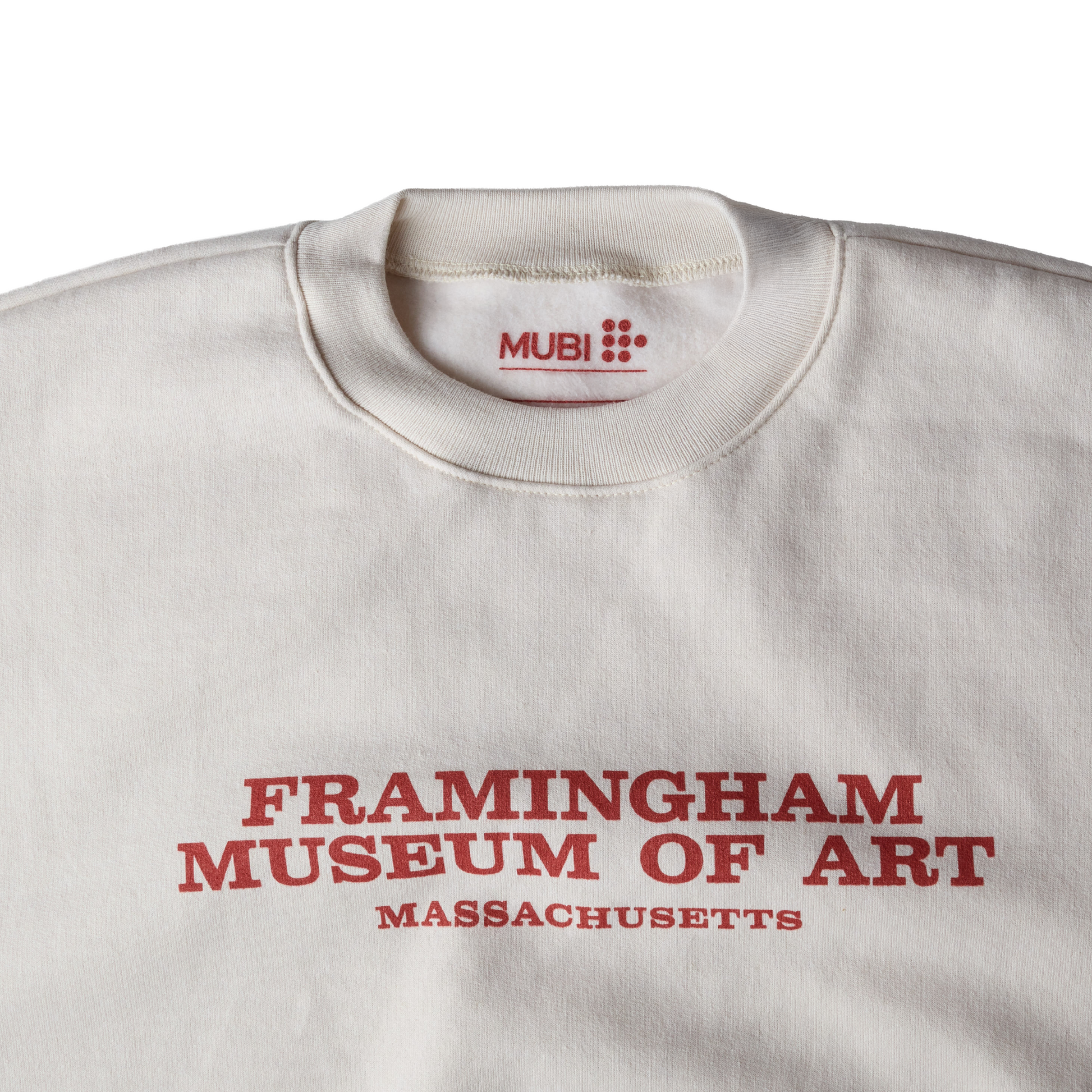 Close-up of THE MASTERMIND cream sweatshirt and the "FRAMINGHAM MUSEUM OF ART MASSACHUSETTS" on the front